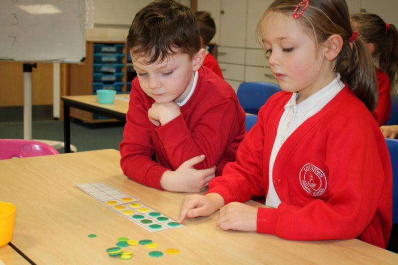 children using counters at a table for maths